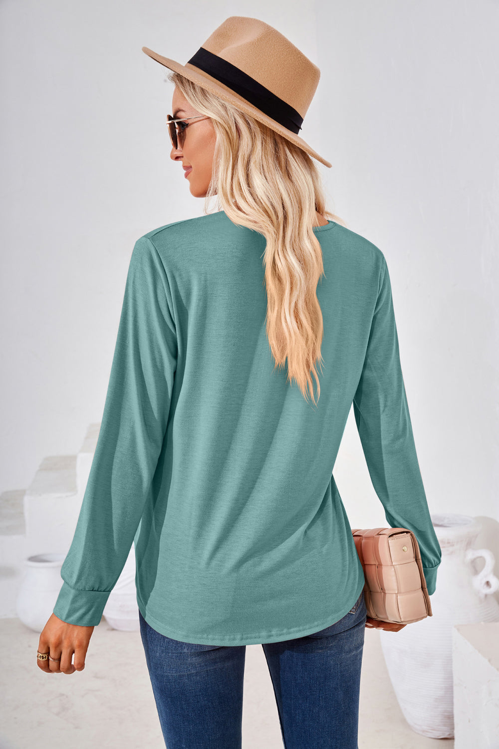 Woman wearing a Square Neck Ruched Long Sleeve Blouse with a hat, showcasing the back view in a stylish setting.