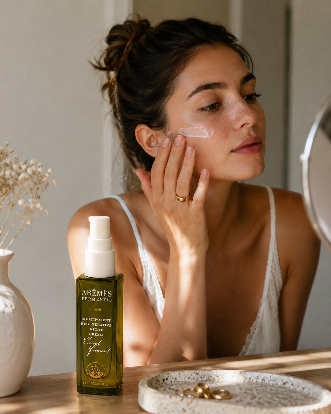 Model applying Multipotent Night Cream on her face, showcasing its overnight skin care benefits.