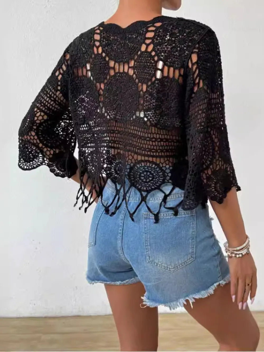 Model showcasing an openwork round neck cover-up paired with denim shorts, perfect for summer styling.