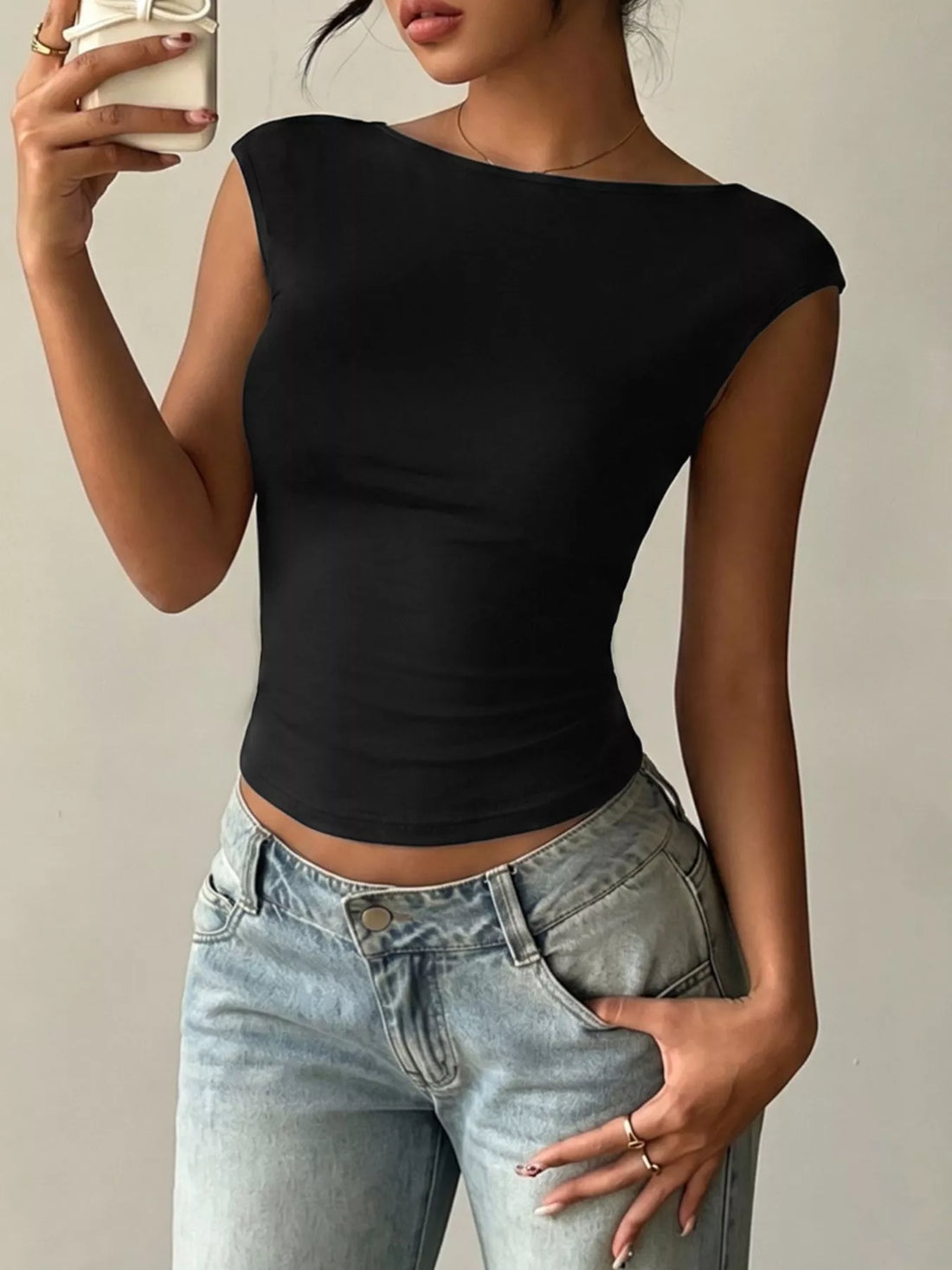 Woman in a black lace detail cap-sleeve t-shirt paired with jeans, showcasing comfort and style.