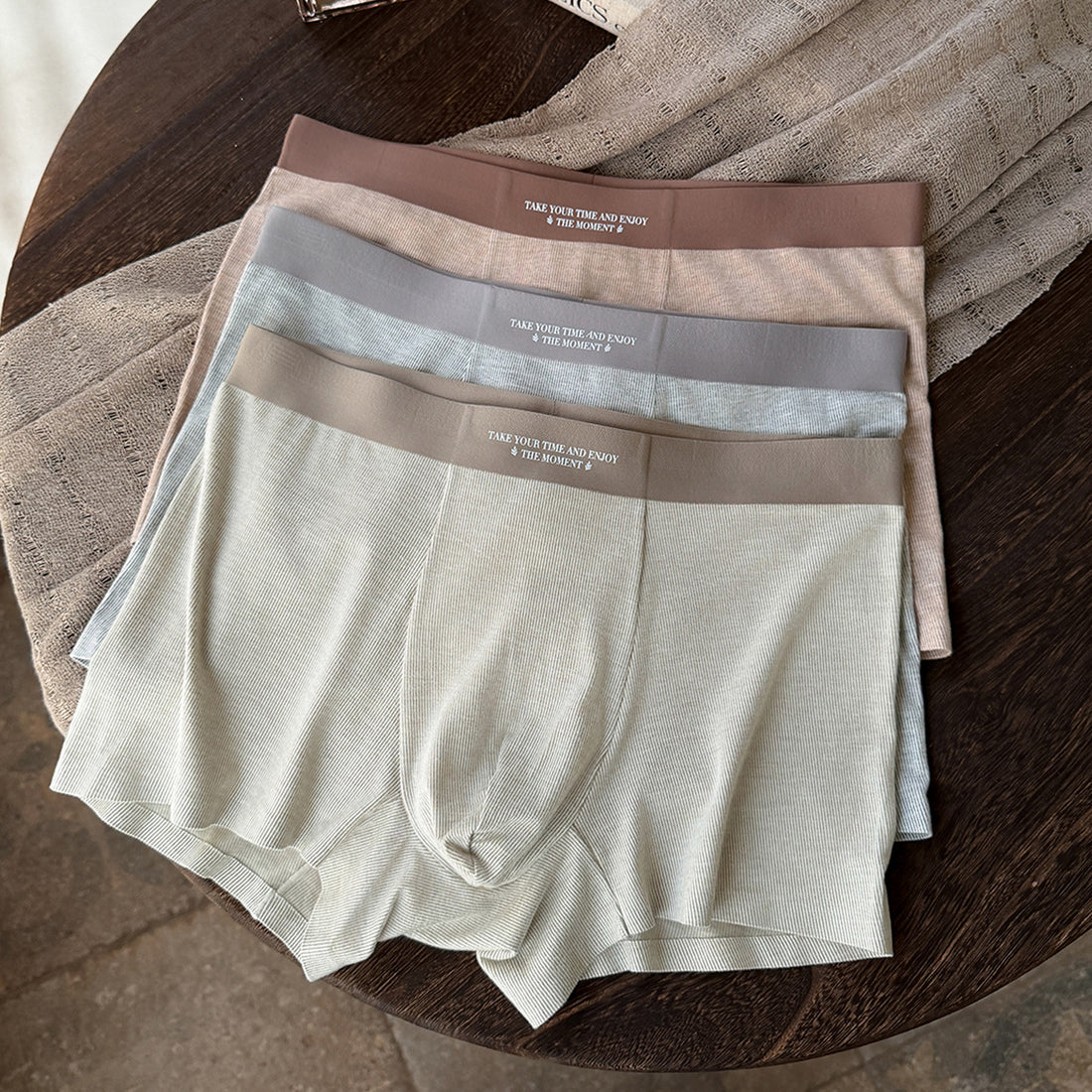 Mens thermal underwear in a 3-pack featuring warm fleece shorts in coordinated colors on a wooden surface.