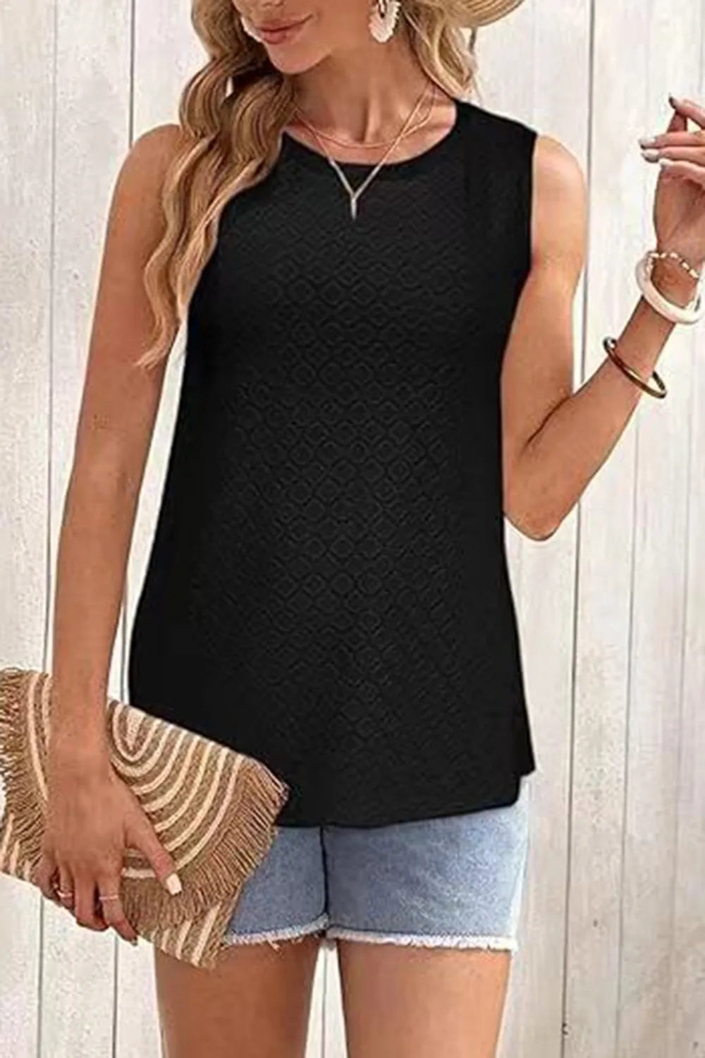 Woman wearing Eyelet Round Neck Tank with stylish shorts holding a trendy clutch, showcasing versatile summer fashion.