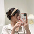 A woman wearing a Solid Color Knit Hair Headband while taking a selfie with her phone.
