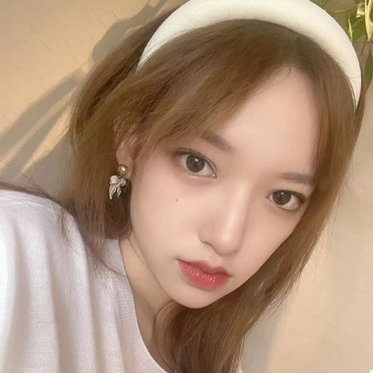 A woman wearing a Solid Color Knit Hair Headband while taking a selfie with her phone.