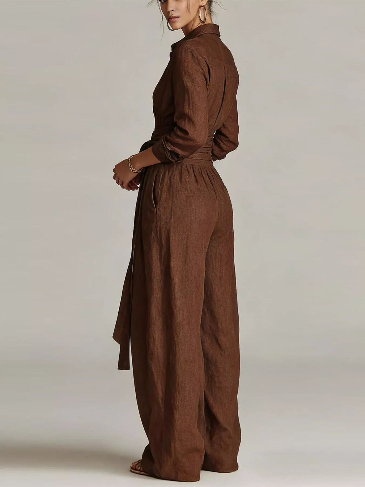 Back view of a woman wearing a Long-Sleeve Waist-Tie Jumpsuit in brown, showcasing its elegant design.