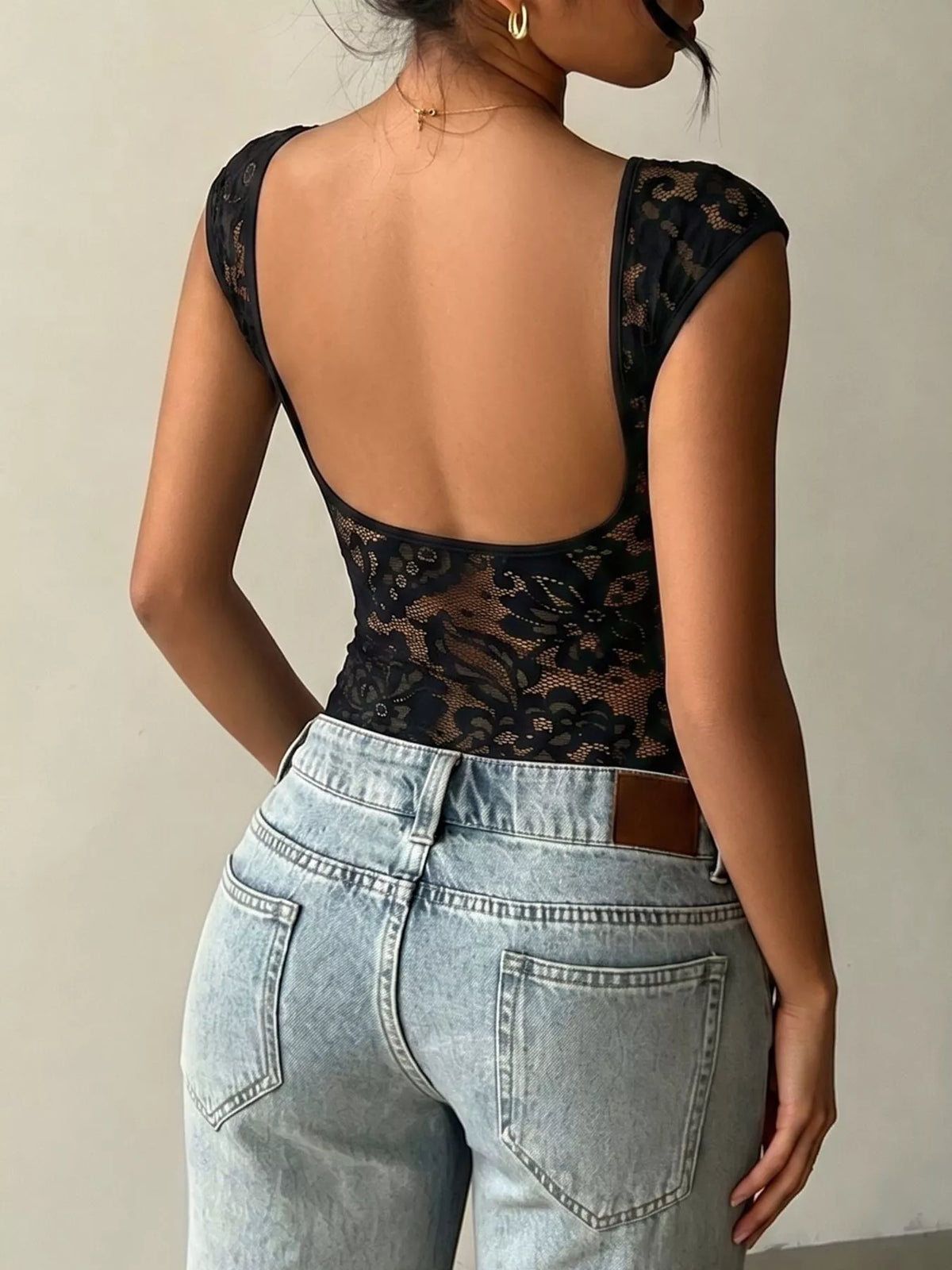Lace Detail Cap-Sleeve T-Shirt showcasing the elegant back design and pairing with high-waisted jeans.
