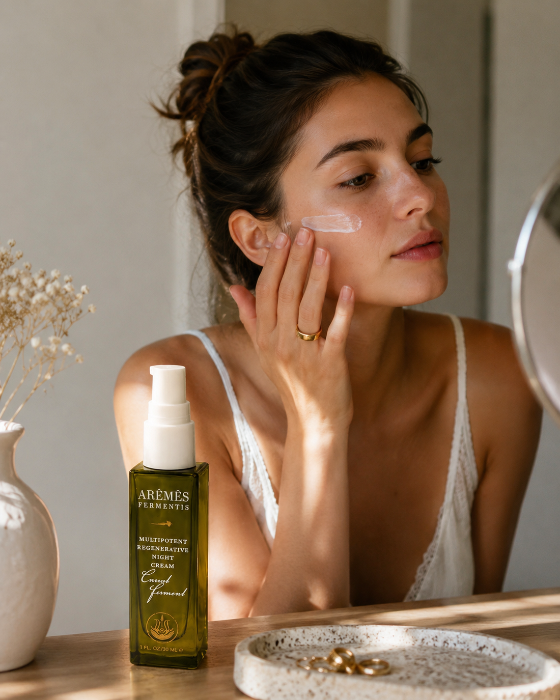 Model applying Multipotent Night Cream on her face, showcasing its overnight skin care benefits.