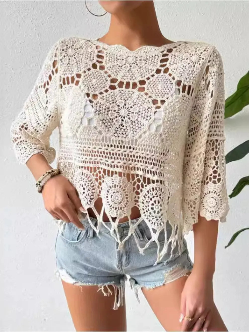 Model showcasing an openwork round neck cover-up paired with denim shorts, perfect for summer styling.