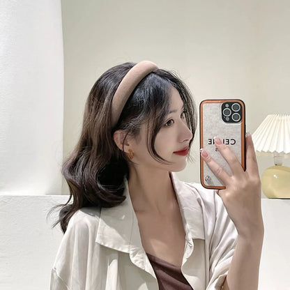 A woman wearing a Solid Color Knit Hair Headband while taking a selfie with her phone.