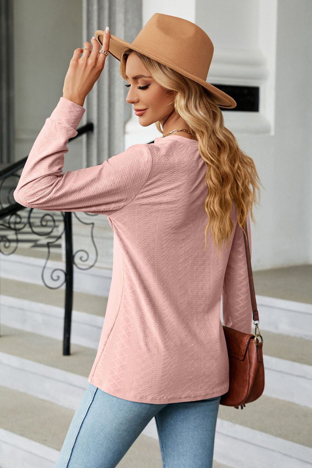 Stylish woman wearing a Notched Neck Buttoned Blouse with long sleeves and a hat, showcasing casual elegance.